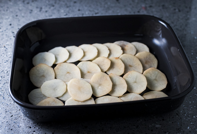 layer of sliced potatoes in a baking dish