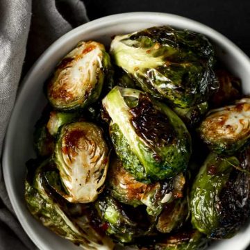 bowls of spicy roasted brussels sprouts with charred edges