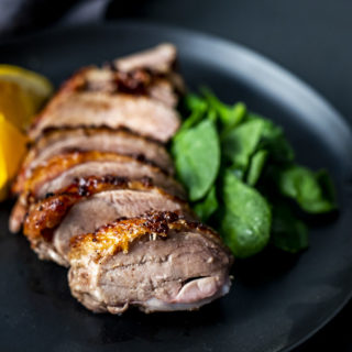 pieces of sliced duck on a plate with greens