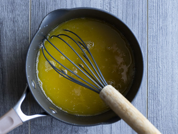 yellow liquid in a saucepan with a whisk.