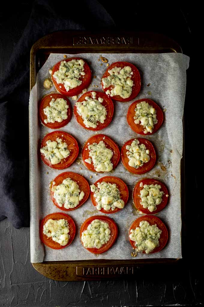 broiled tomatoes covered in cheese on a baking sheet