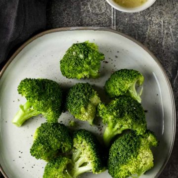 broccoli on a plate with lemon butter on the side