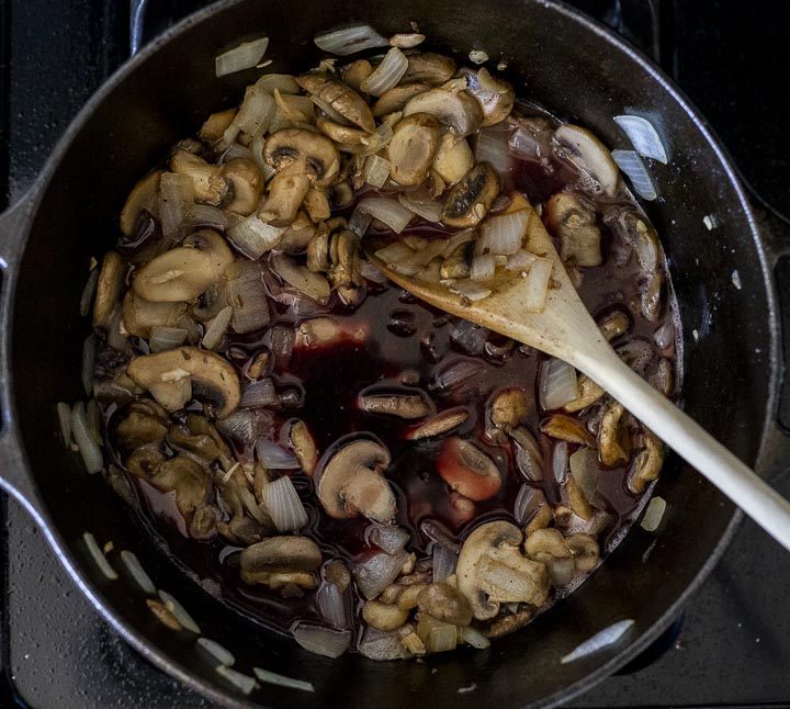 onions and mushrooms cooking with seasonings in a pot