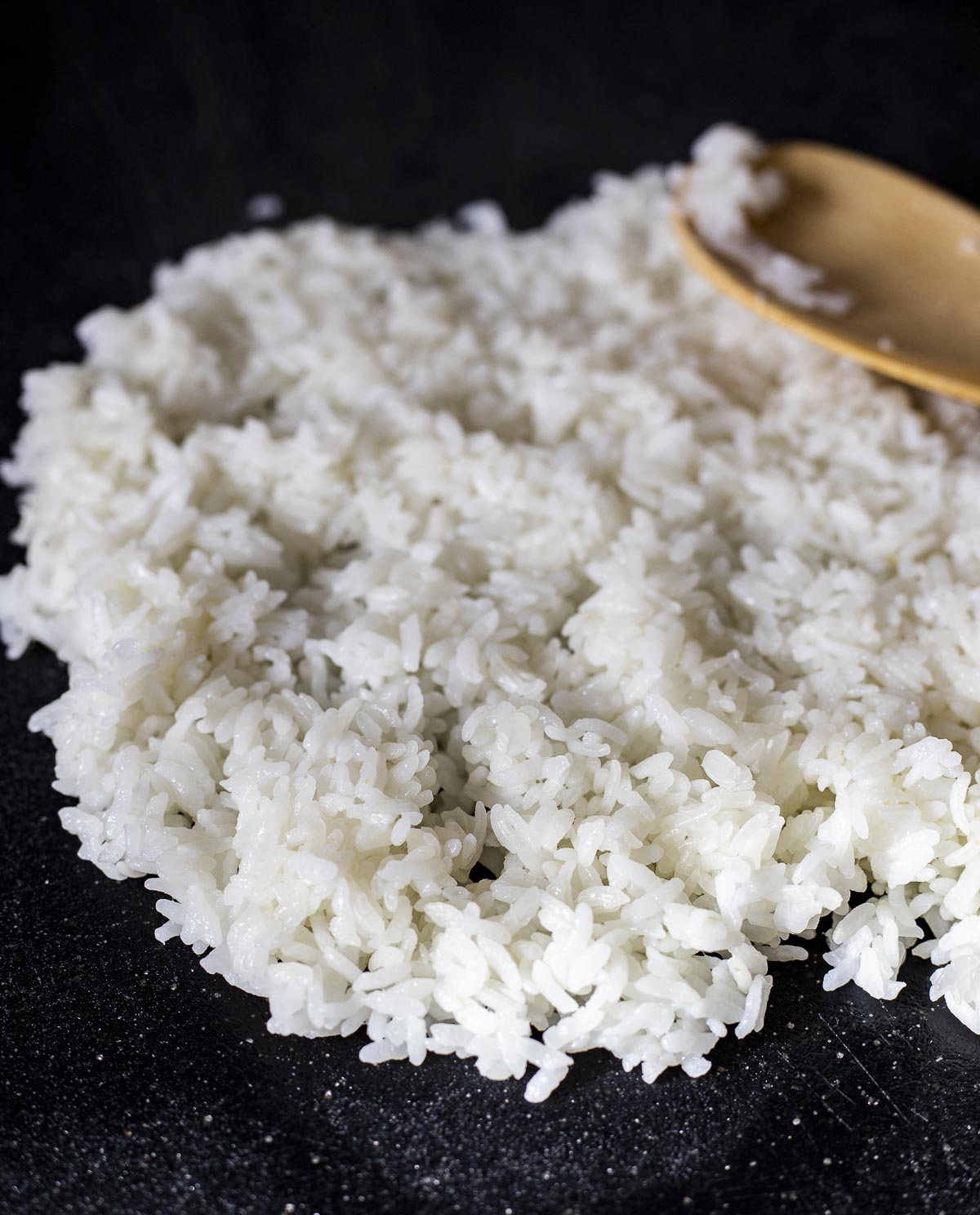 rice spread on a board with a wooden spoon.