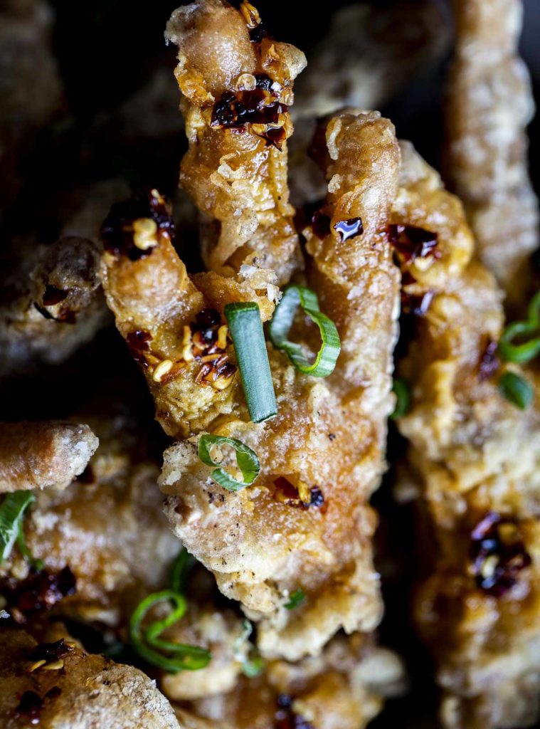 a close up of a fried chicken foot with green onion garnish