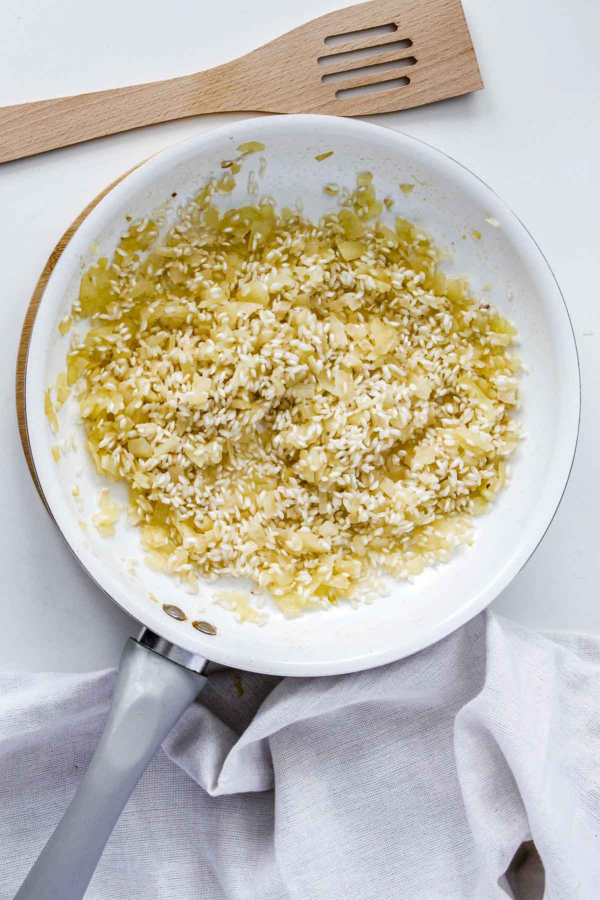 Arborio rice added to a pan of onions and garlic.