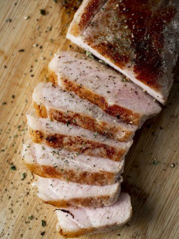 sliced pork on a surface with cracked pepper