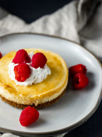 Air fryer cheesecake with whipped cream and raspberries.