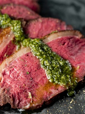 Close up of sliced picanha with sauce on top.