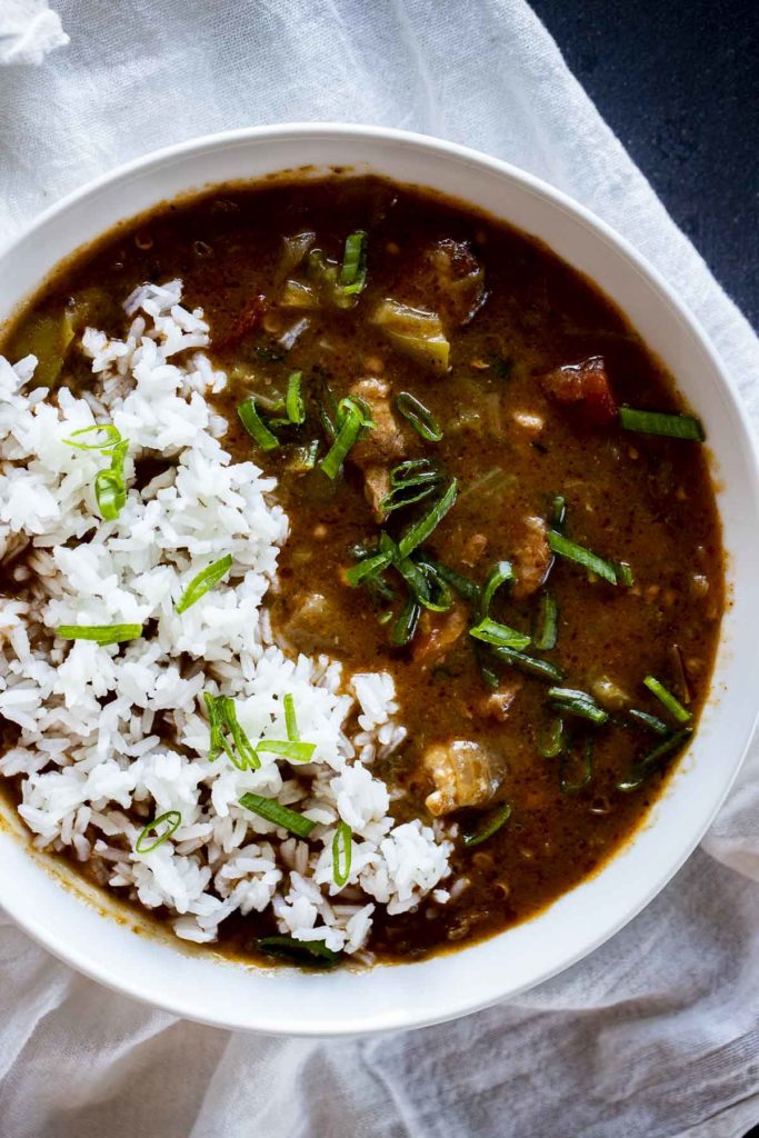Instant Pot gumbo in a white bowl with rice on top..