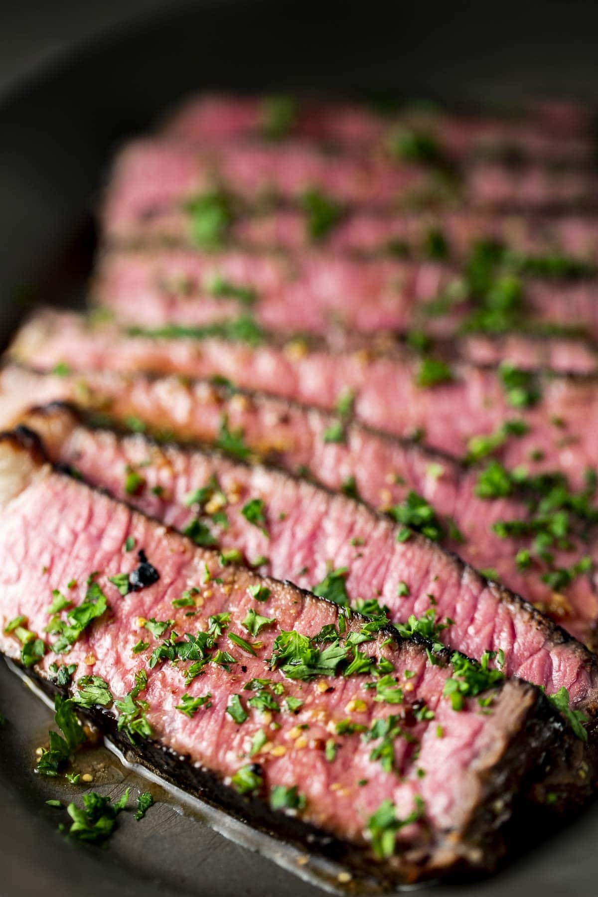 Steak cut across the grain and topped with chopped herbs.
