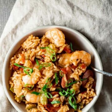 Jambalaya in a white bowl and topped with chopped green onions.