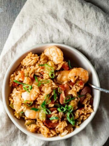 Jambalaya in a white bowl and topped with chopped green onions.