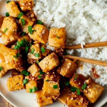 view of tofu and rice on a white plate with chopsticks