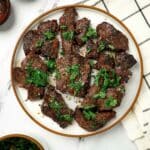 Slices of beef heart on a plate with green herbs