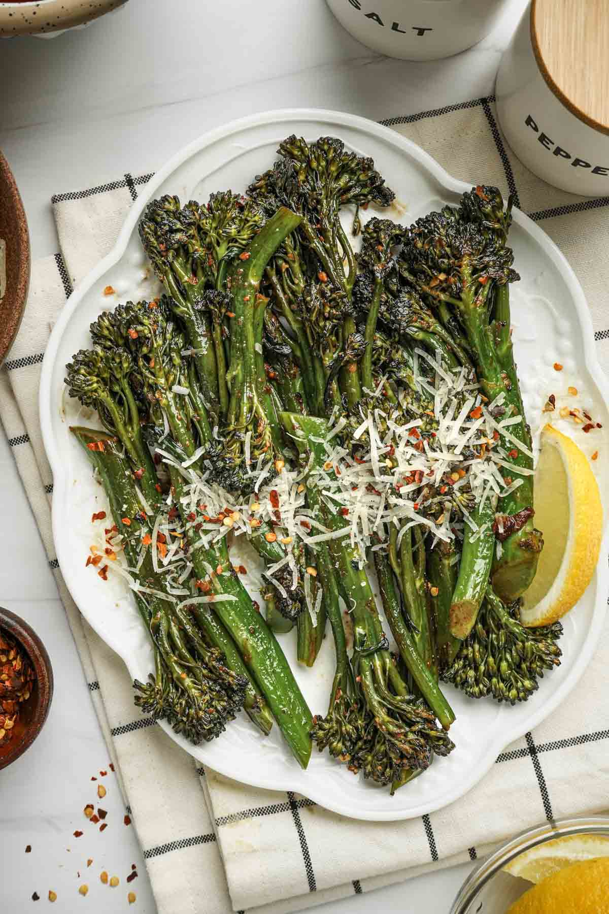 cooked green broccoletti on a plate with parmesan cheese