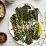 broccoletti on a plate with cheese, chilies and lemon wedge on the side