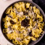 a dish of creamy pasta with black truffles shaved on tp