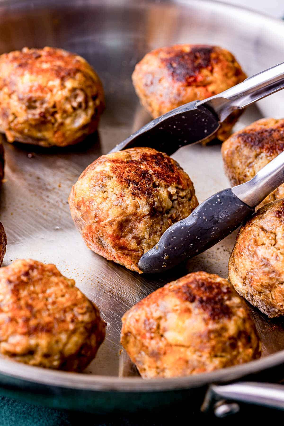 meatballs being browned in a skillet