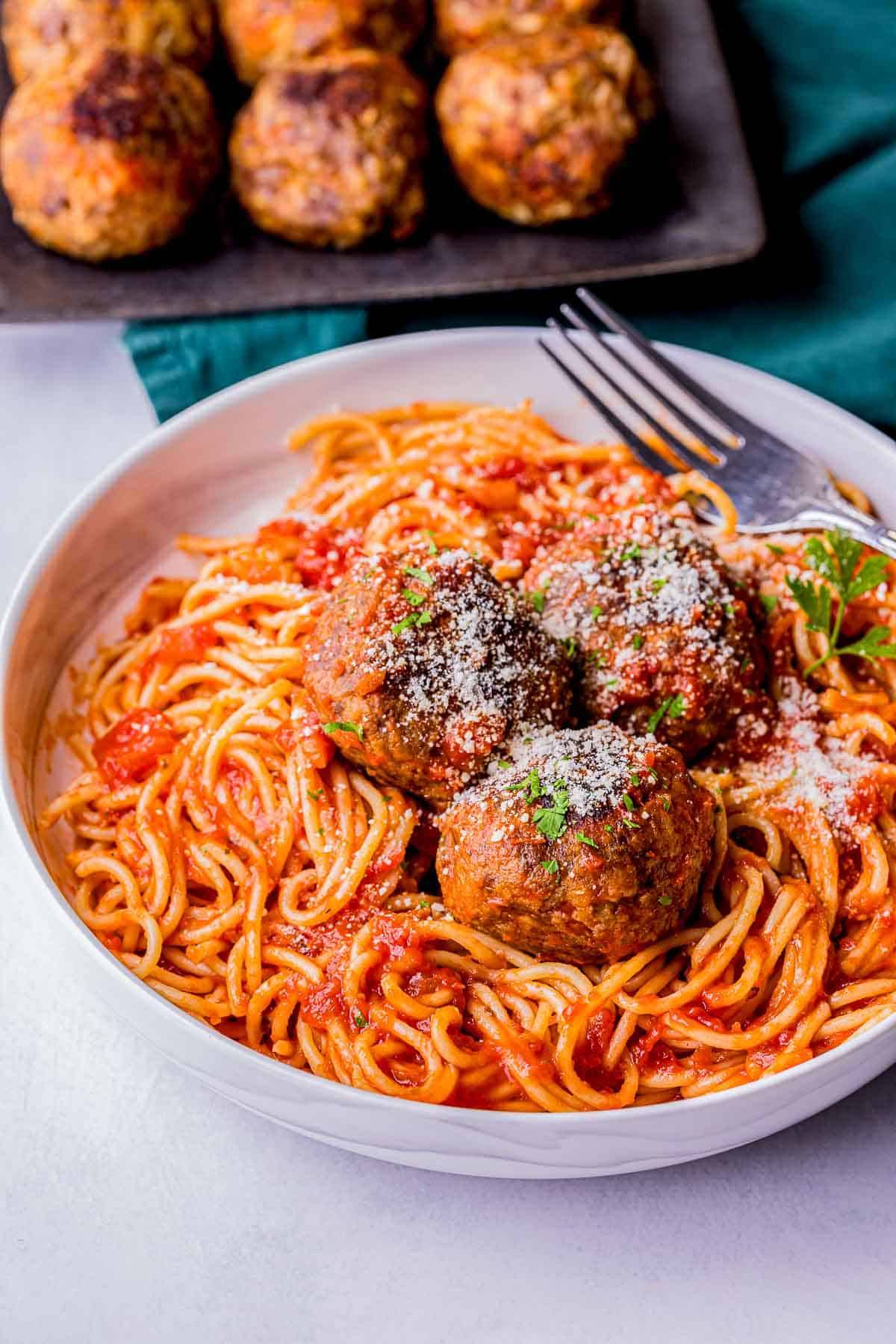 spaghetti and meatballs in a bowl with parmesan cheese