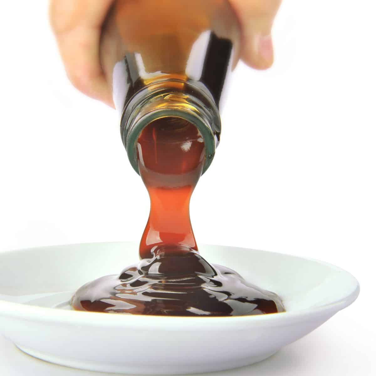 a bottle pouring a thick dark liquid into a bowl