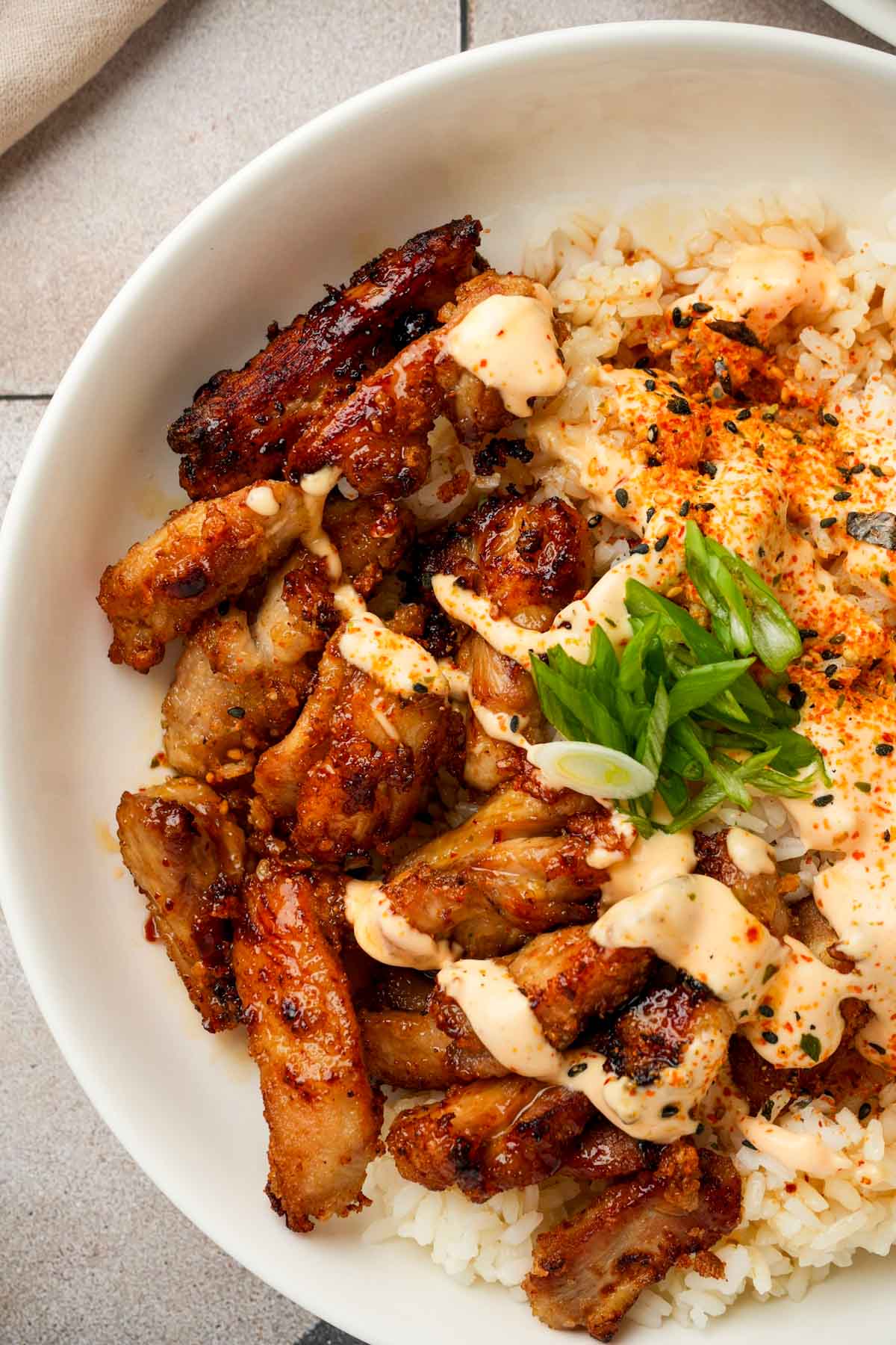 karaage in a bowl with rice and green onions