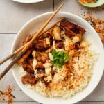 a bowl of karaage don (fried chicken rice bowl) with chopsticks and green onions