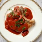 A glazed pork chops smothered in tomato sauce on a plate