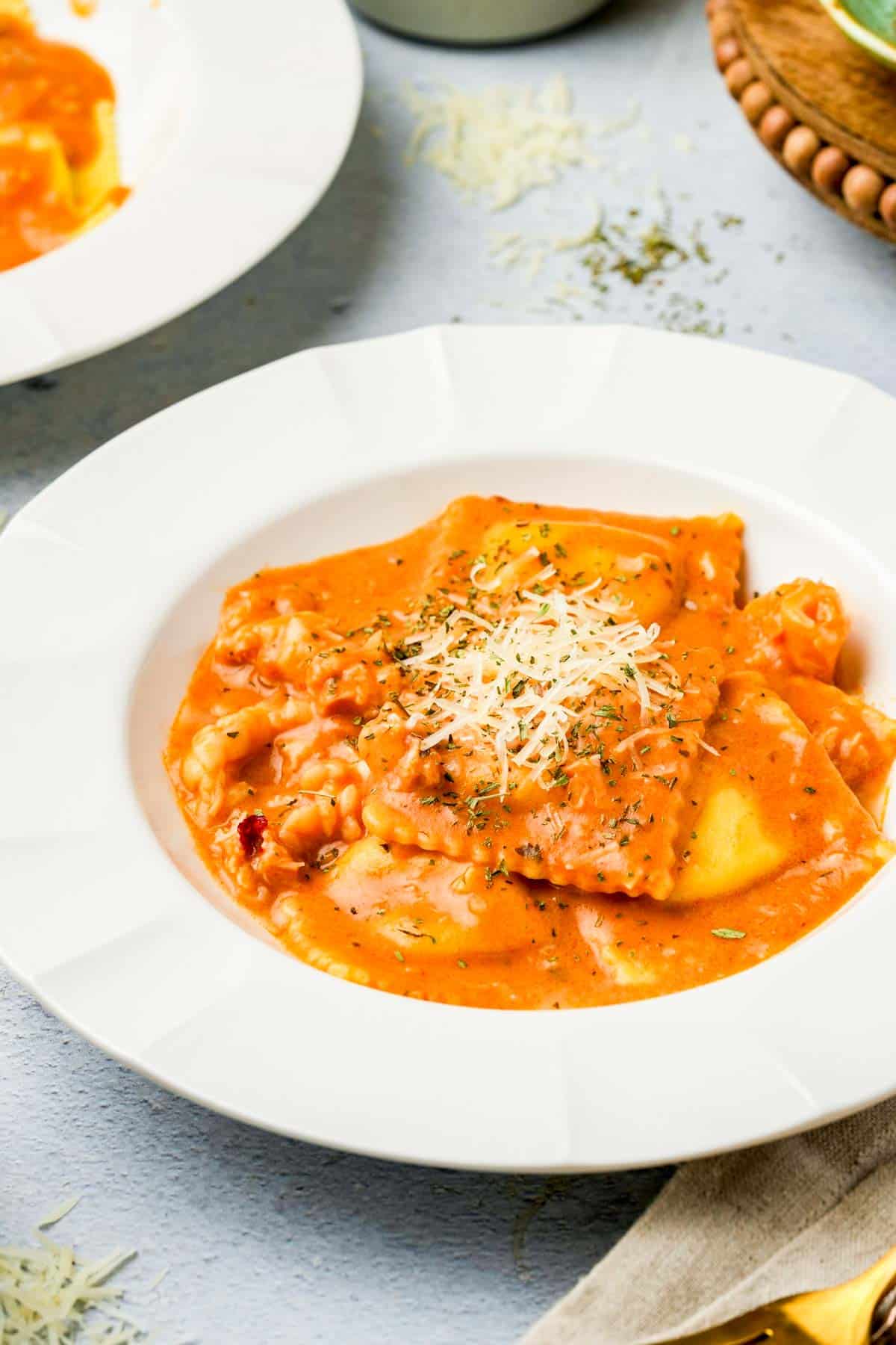 a bowl of ravioli covered with homemade lobster ravioli sauce and grated parmesan.