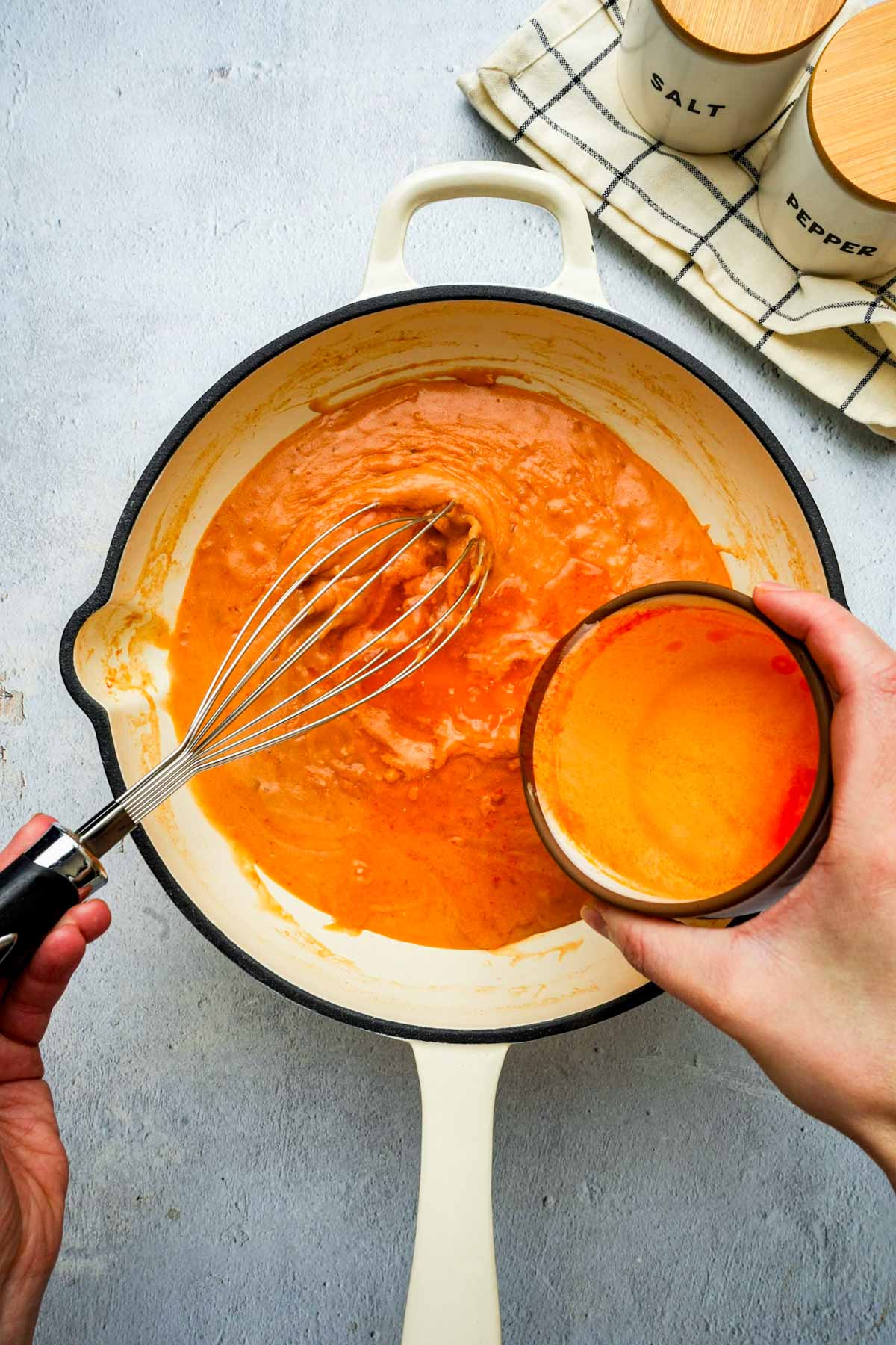 orange sauce being whisked in a skillet