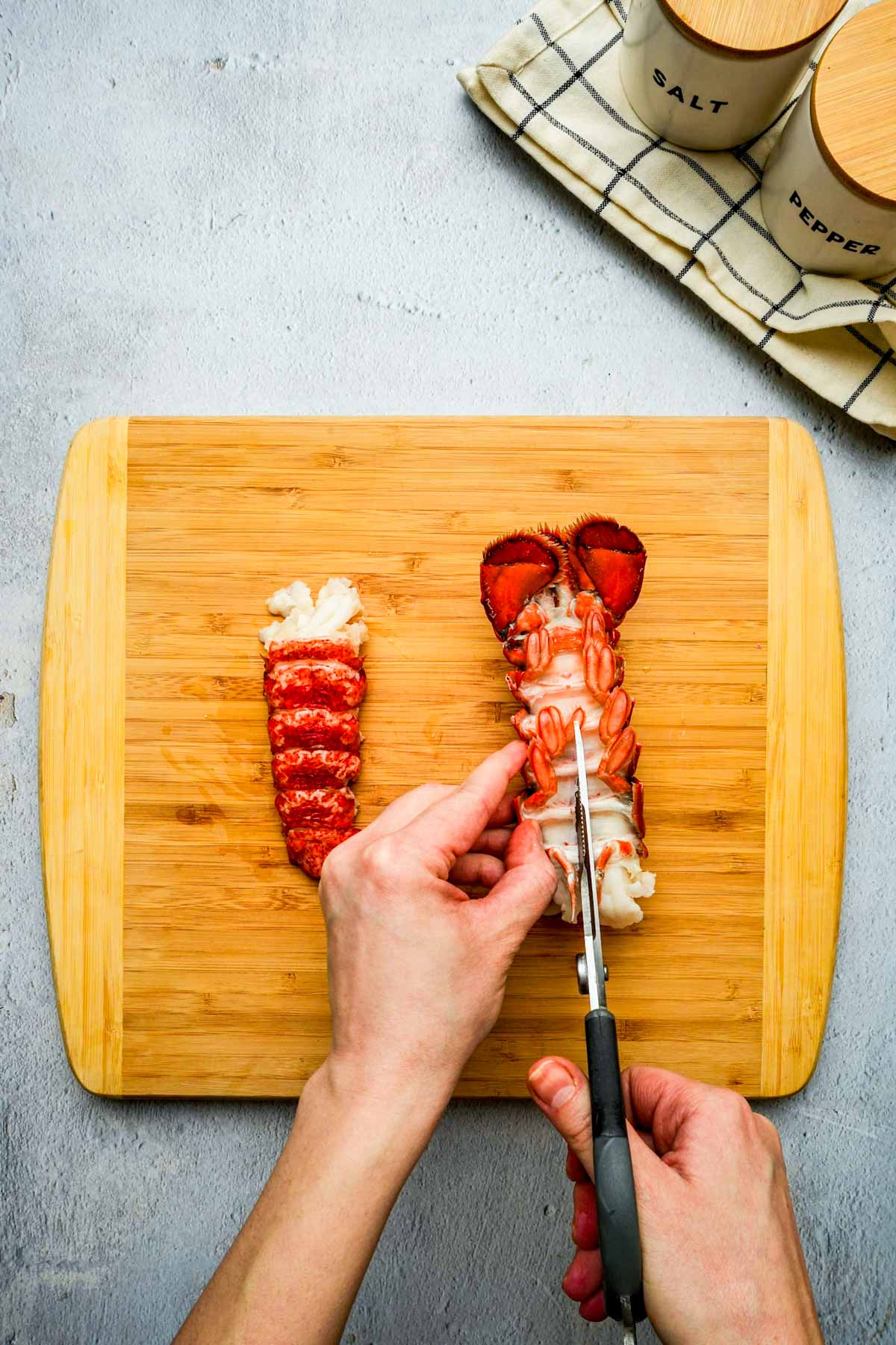 lobster tail being cut open with kitchen shears.