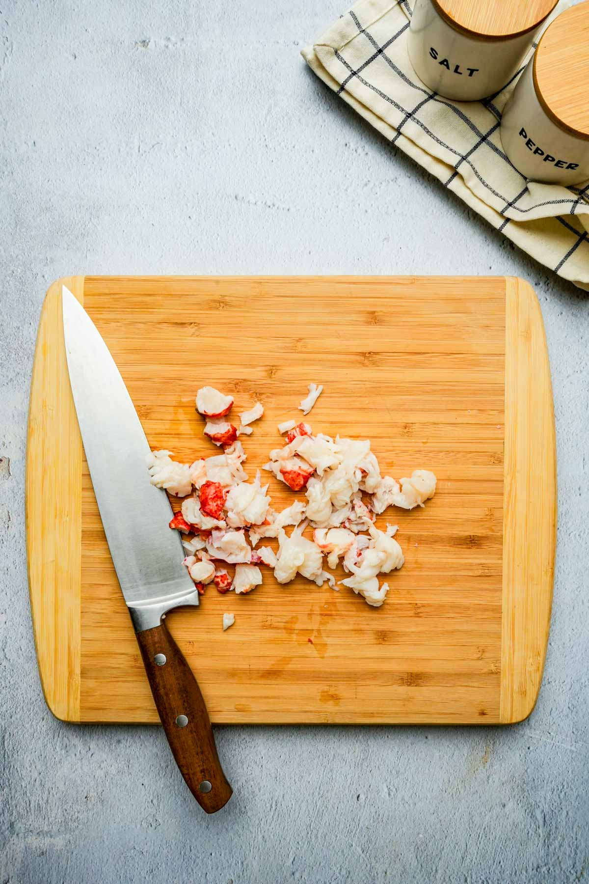 chopped up lobster meat on a cutting board.