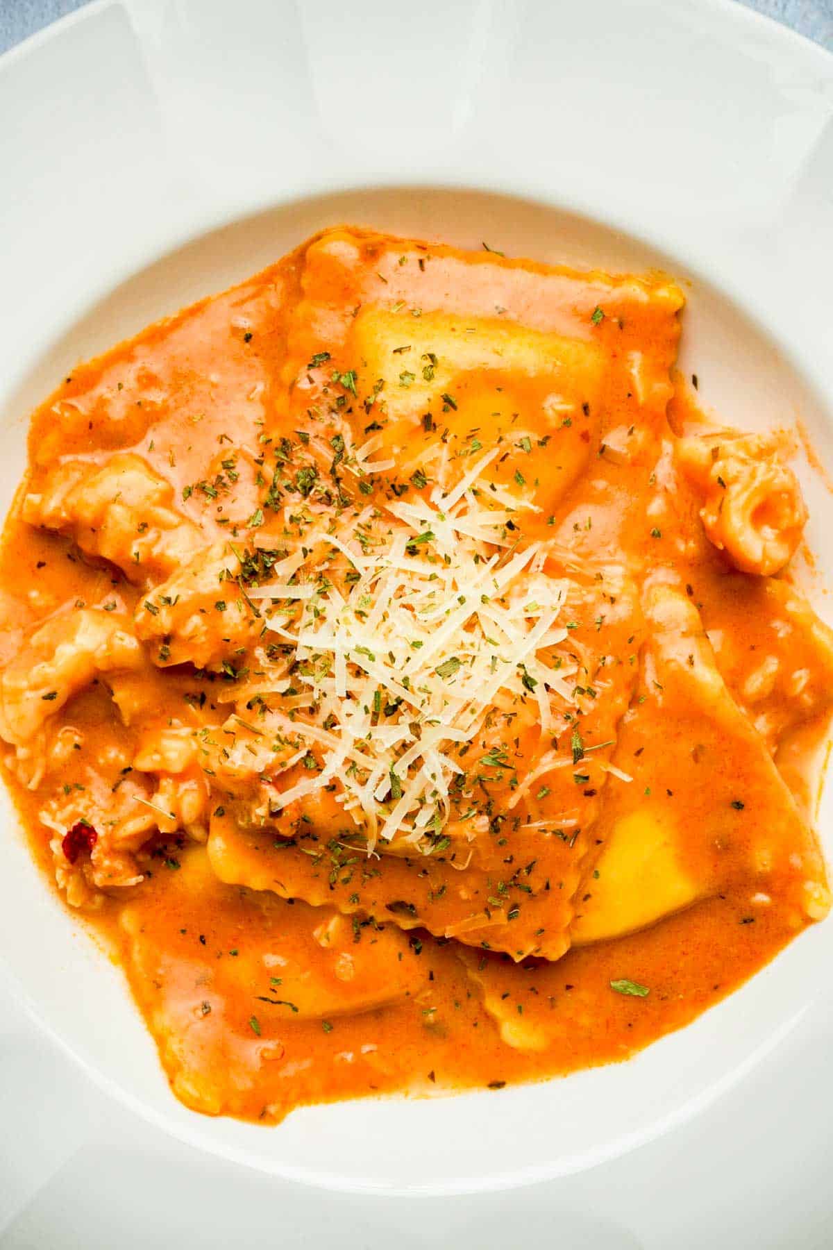 a bowl of lobster ravioli with cream sauce and parmesan cheese on top.
