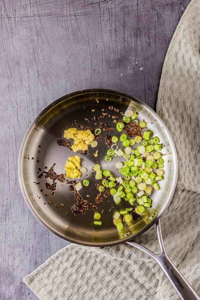 green onions and spices cooking in a skillet