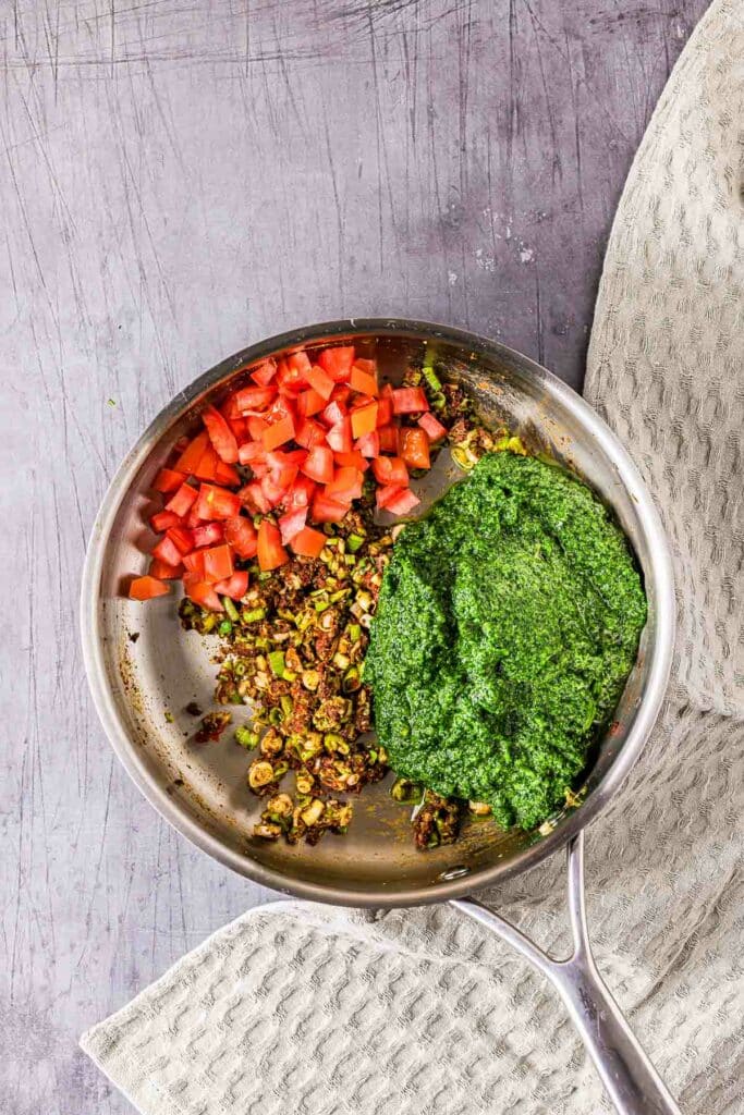 green puree and tomatoes added to a skillet