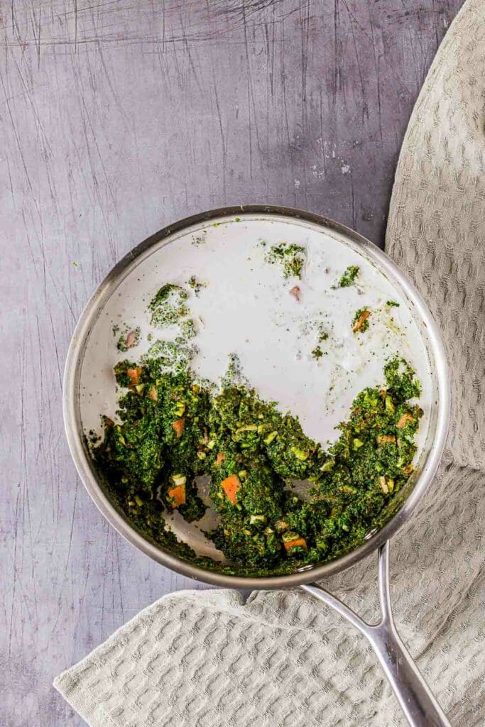 a green and white sauce being mixed together in a skillet