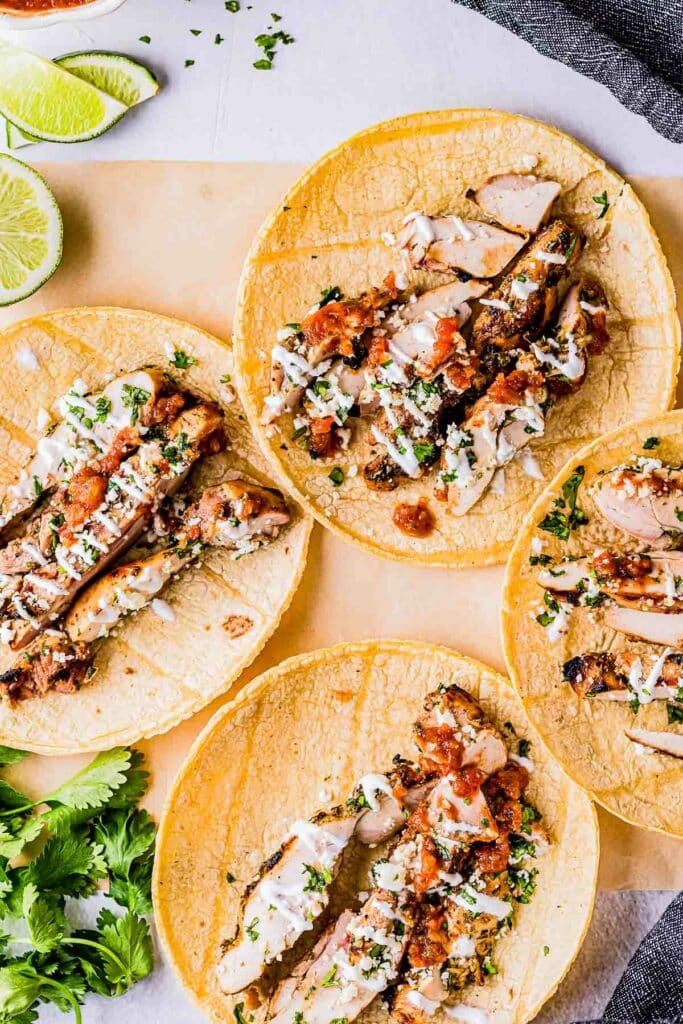 tacos de pollo being made on corn tortillas with cilantro, crema and salsa