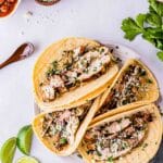 a plate of shredded chicken tacos on a plate with condiments