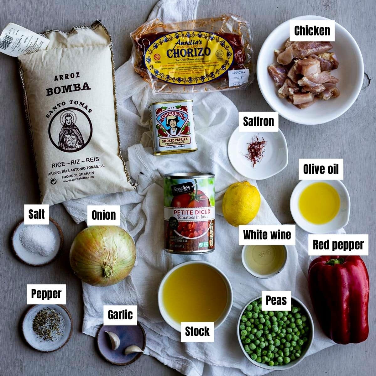 ingredients for chicken and chorizo paella on a gray board.