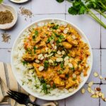 chicken in sauce with rice and cilantro on a plate