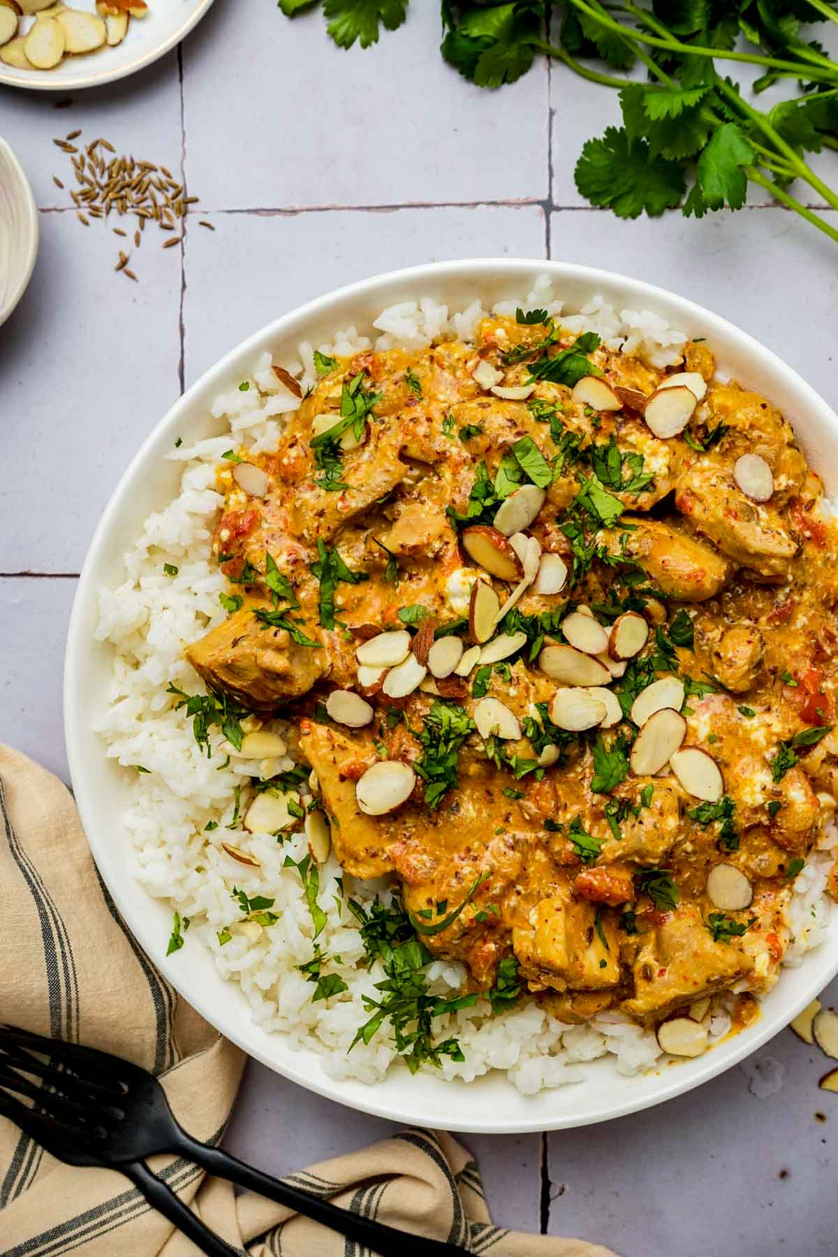chicken pasanda and rice garnished with almonds and herbs.