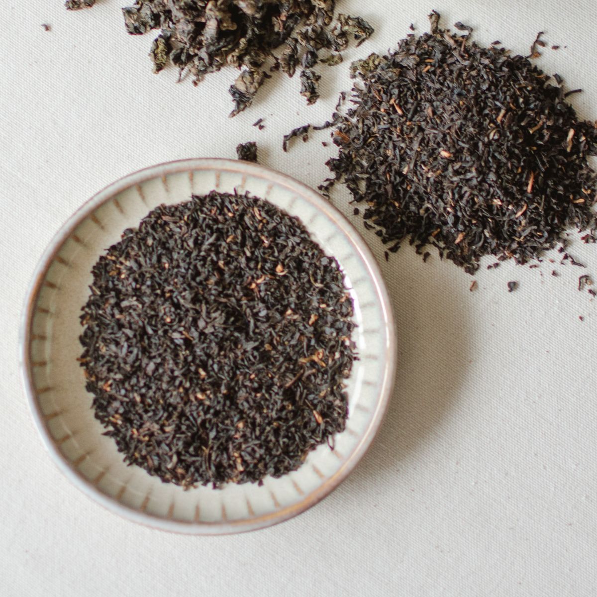 dried black tea leaves in a white bowl