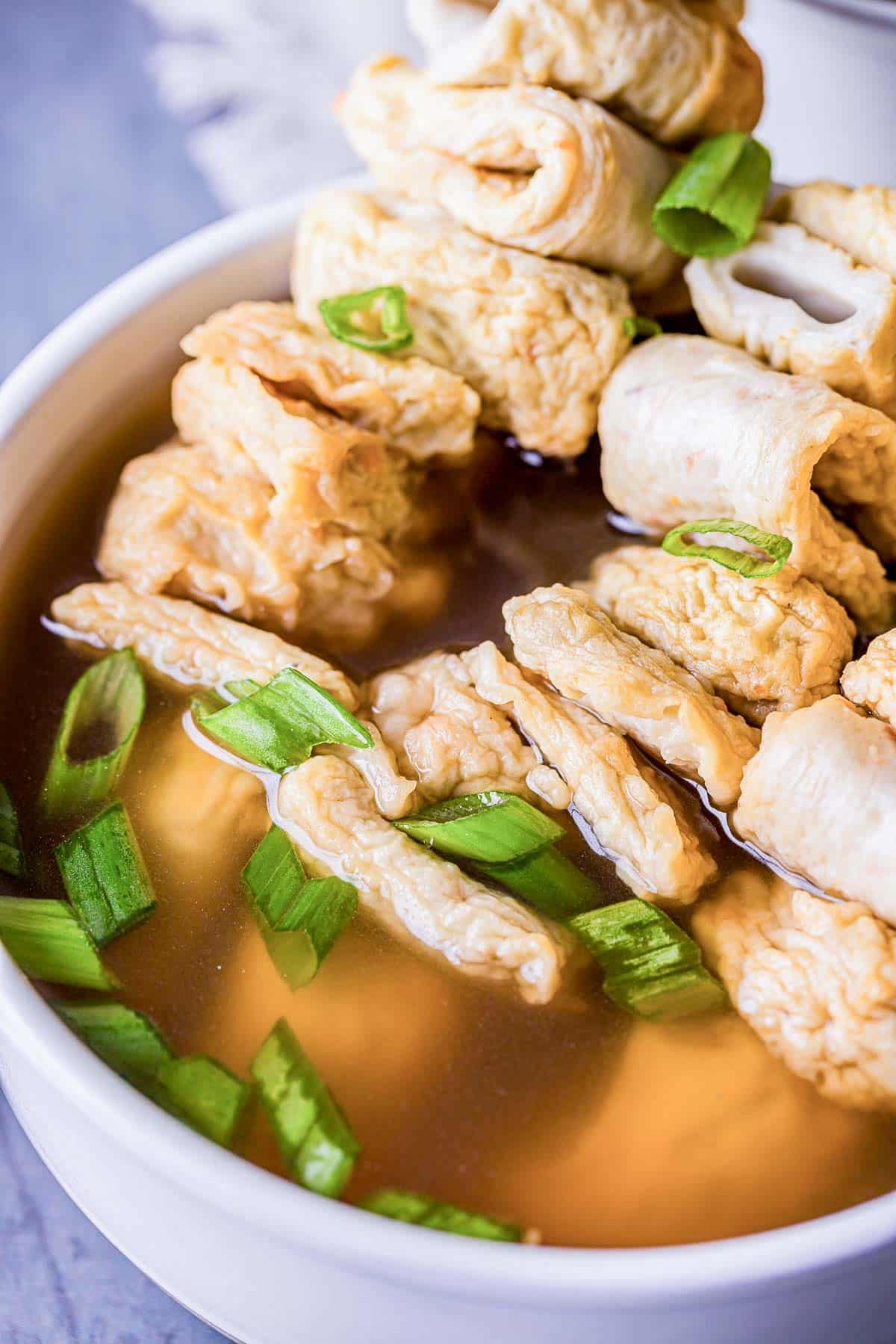 Korean fish cakes on skewers in a bowl of broth.