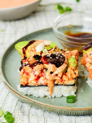 a slice of sushi bake on a plate with sauce on top.