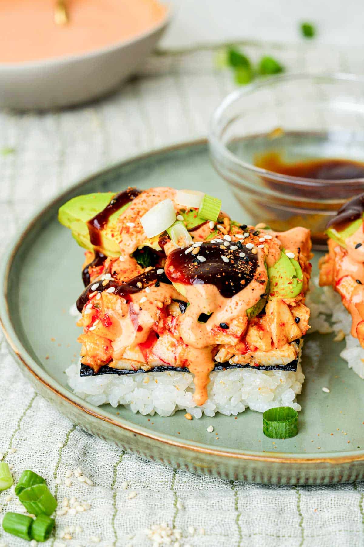 a slice of sushi bake on a plate with sauce on top.