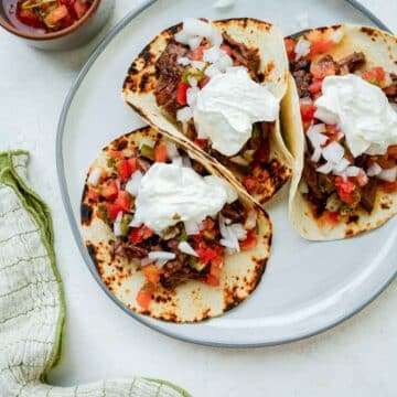a plate of mexican beef tacos with sour cream