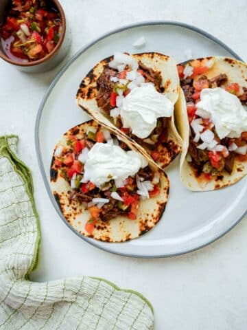 a plate of mexican beef tacos with sour cream