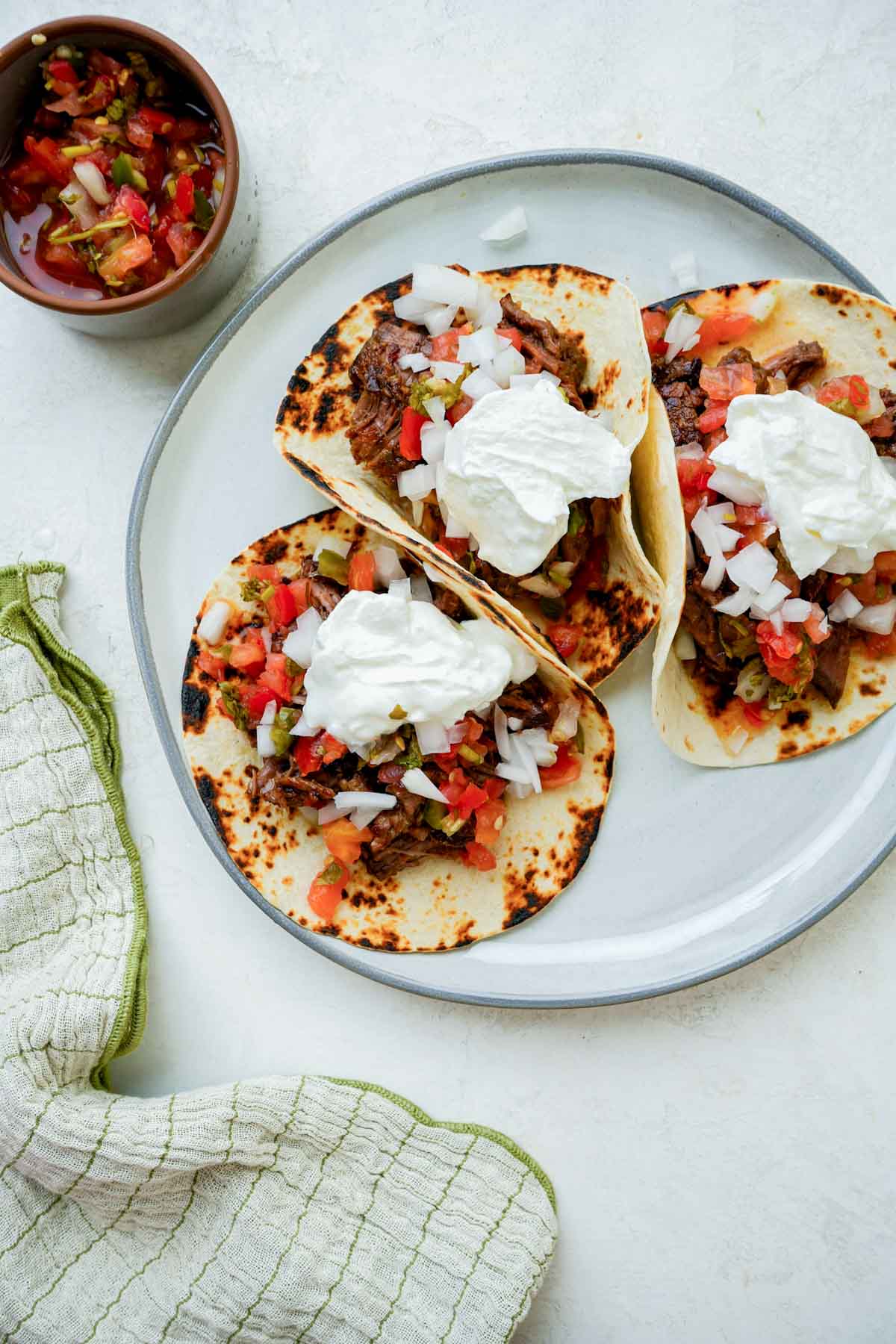 a plate of mexican beef tacos with sour cream