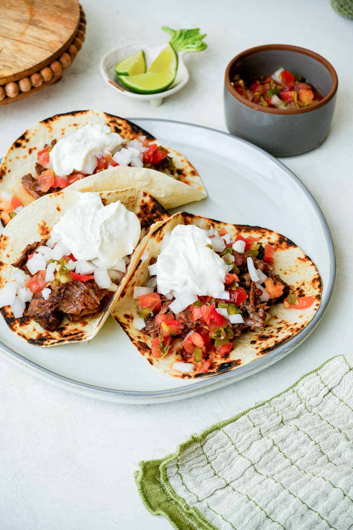 beef tacos with tomato salsa and sour cream on a plate.