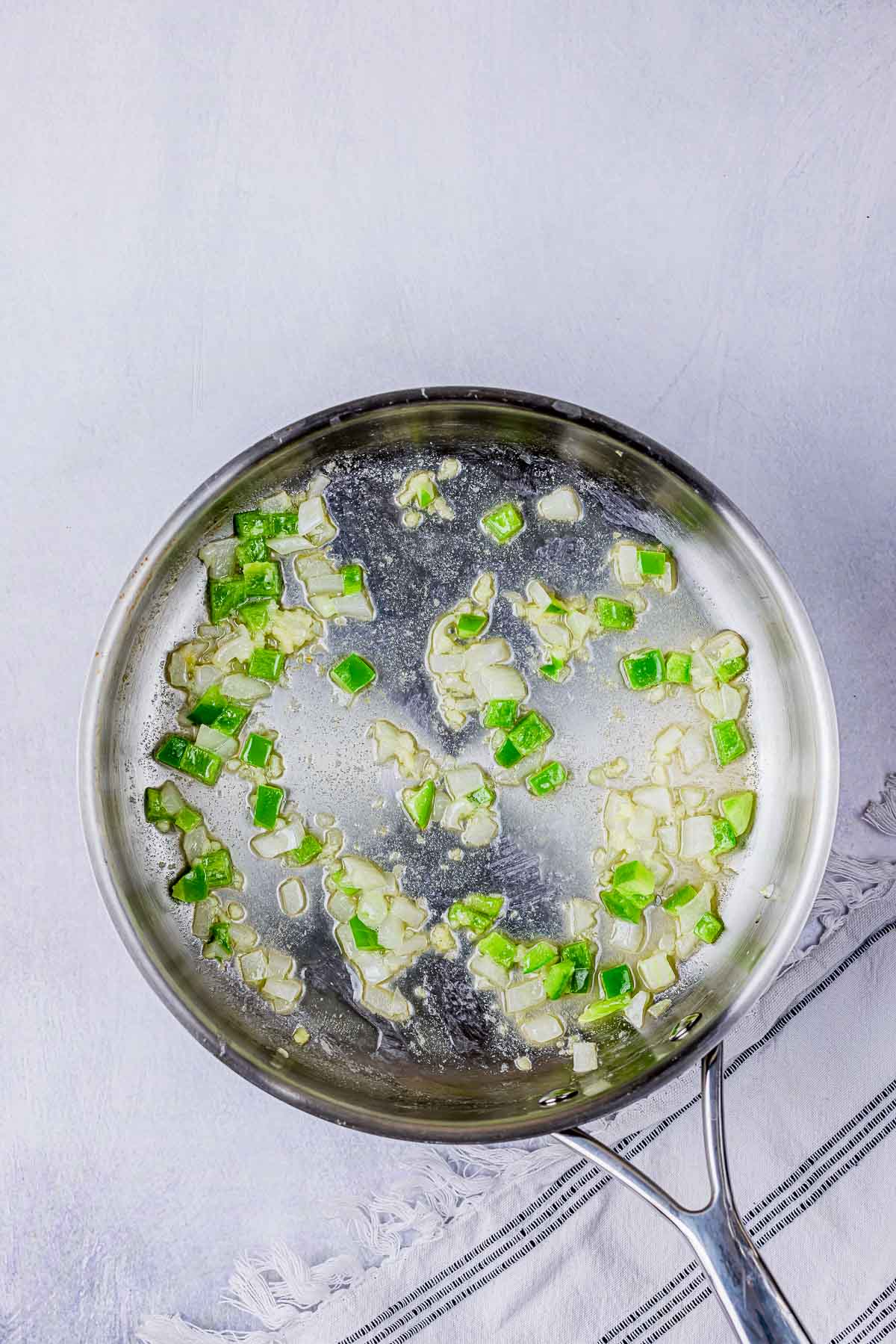 onions and green peppers cooking in a skillet.